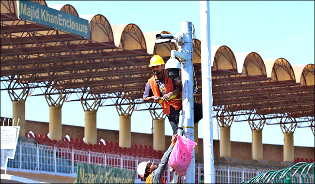 A technician installs a security camera at the Gaddafi Stadium