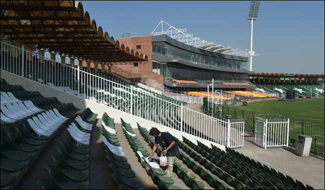 Worker paints chairs at the Gaddafi Cricket Stadium