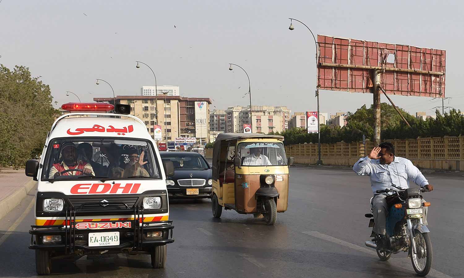A motorcyclist (R) pays his respects to Abdul Sattar Edhi (2nd L), as he travels to his office in Karachi.