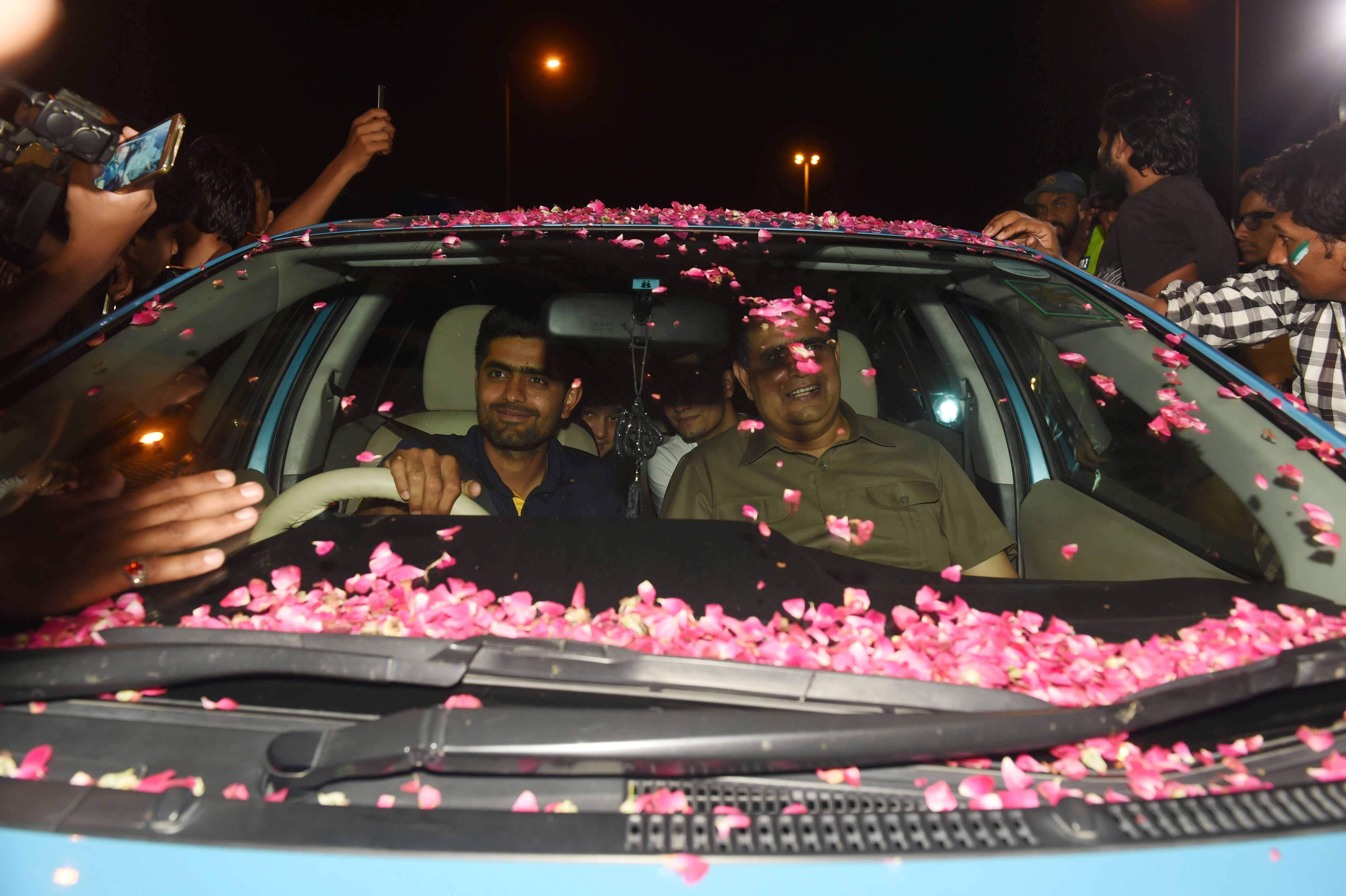 Babar Azam (centre L) is surrounded by fans as he drives his car upon his arrival from London outside the Allama Iqbal International airport in Lahore.