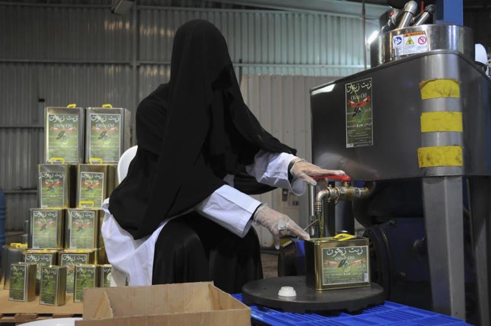 A veiled worker fills a can with olive oil at a factory for pickling olives in Tabuk, October 23, 2013. REUTERS