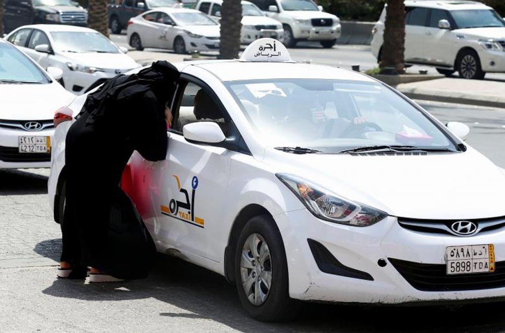 A woman speaks with a taxi driver to get a ride in Riyadh, September 28, 2017. REUTERS