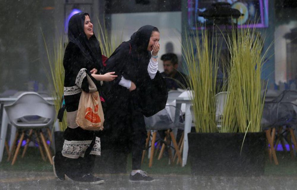 Women run for cover from rain in Riyadh, February 16, 2017. REUTERS