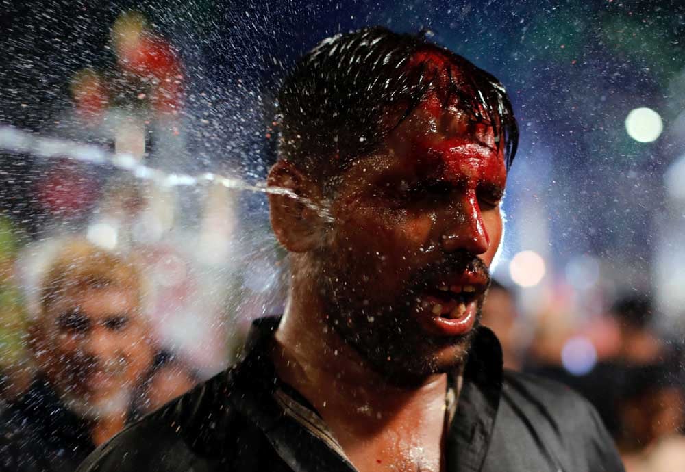 A man is sprayed with rose water as he flagellates himself during a Muharram procession ahead of Ashura in Mumbai
