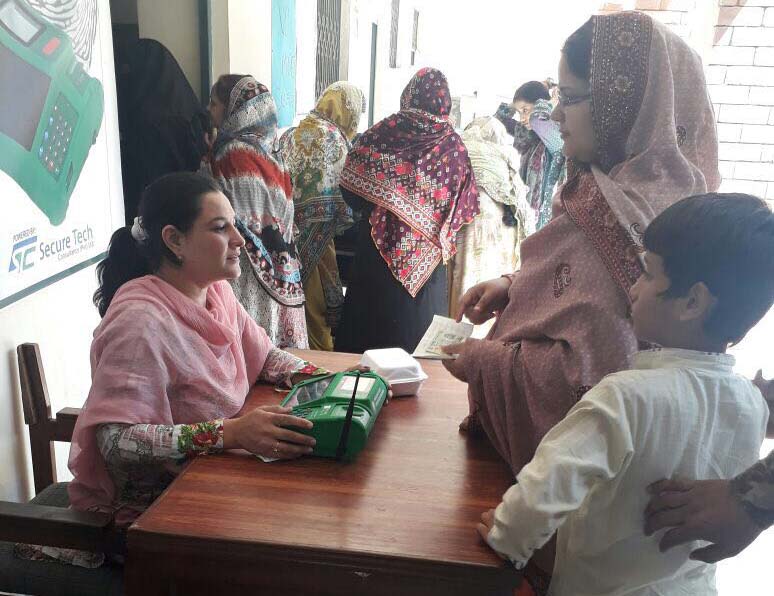 A polling staffer is seen supervising voting on biometric voting machine.