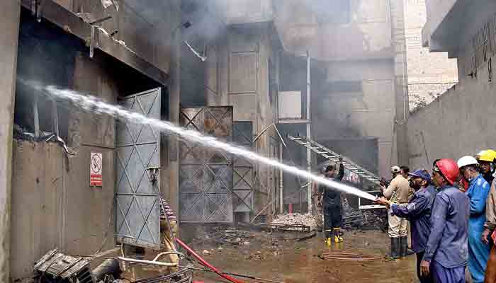 A team of firefighters and others rescue works busy in extinguishing fire, rescue the people after a fire broke out at a chemical factory in Mehran Town in Korangi Industrial Area ,at least 17 people killed and several injured in the incident. -APP