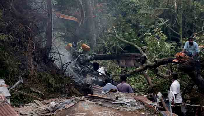 People stand near the debris of the Russian-made Mi-17V5 helicopter after it crashed near the town of Coonoor in the southern state of Tamil Nadu, India, December 8, 2021.