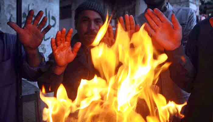 People sitting around fire to keep them warm during chilled weather in Rawalpindi. -APP