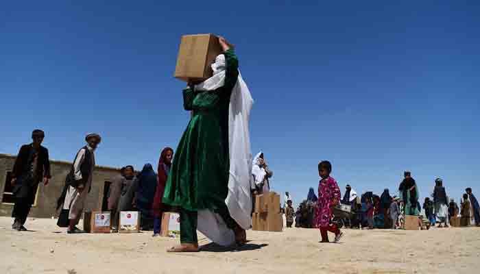 In this file photo taken on May 03, 2020, an internally displaced woman carries aid distributed during the Holy month of Ramadan in a refugee camp on the outskirts of Mazar-i-Sharif, Afghanistan. The UN Security Council on December 22, 2021, unanimously adopted a US-proposed resolution that facilitates humanitarian aid to Afghanistan, which is on the verge of economic collapse. -AFP