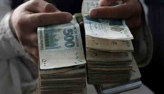 A currency dealer holding Pakistani currency. -PPI