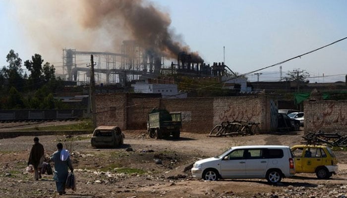 In this undated photo, people seen passing by a factory in Peshawars outskirts. Photo: AFP