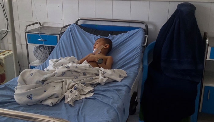 An Afghan woman sits next to a child receiving treatment at a hospital after he was wounded in a bomb blast in Kunduz. Photo: AFP