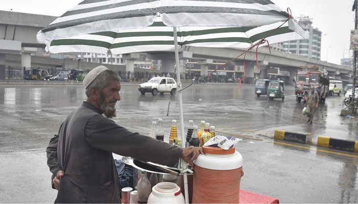 A vendor covered his stall with an umbrella during rain in Peshawar on June 21, 2022. Photo: INP