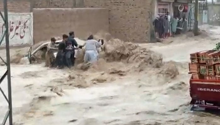 People seen making effort to take people from the car torrent of rainwater to safety in a suburb of Quetta on July 5, 2022. Photo: Screengrab of a Twitter videoo.