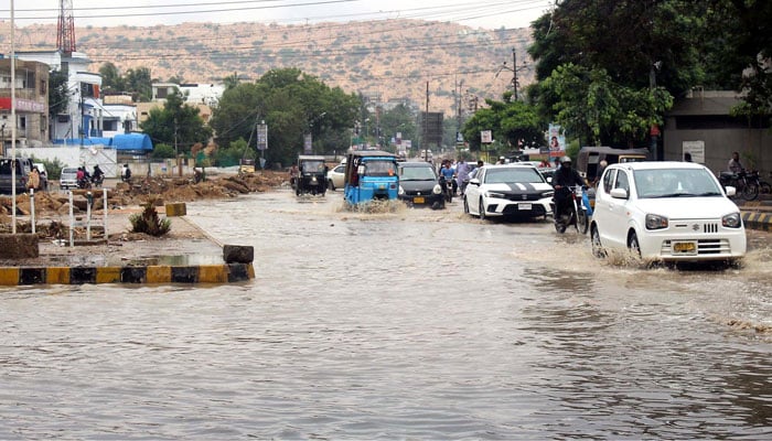 Vehicles passing through rainwater accumulated on KDA Chowrangi in Karachi after rains on July 7. 2022. Photo: INP