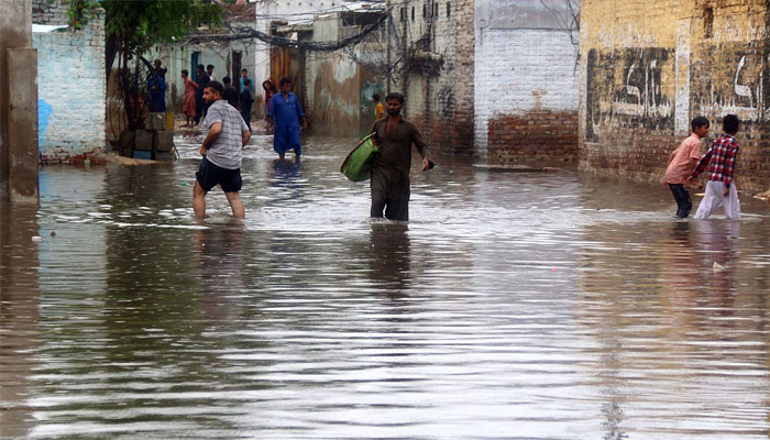 Commuters wade through a flooded road after heavy rainfall at Main Qasimabad road in the city.— ONLINE /Nadem Khawar