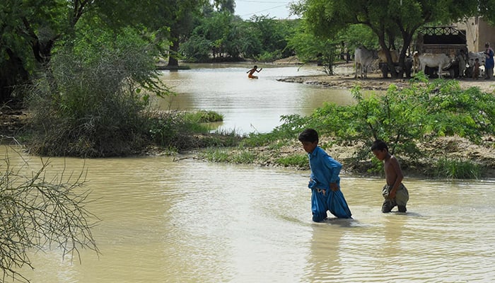 Childern wade across at a flood-affected town called Gandawah in Jhal Magsi district, southwestern province of Balochistan, Pakistan on August 2, 2022. — AFP