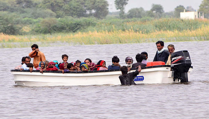 Volunteers rescue flood affected people with help of boat in the flood water at khair muhammad pahwar goht after heavy rain in this areas. —APP /Farhan khan