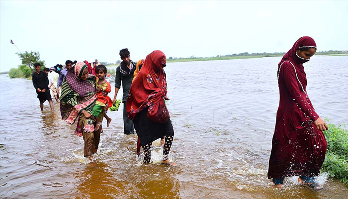 Flood affected people evacuate from flood water at khair muhammad pahwar goht after heavy rain in this areas. &mdash;APP/ Farhan khan