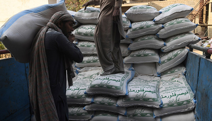 Labourers load sacks of wheat flour at a market in Karachi on January 20, 2020. -AFP