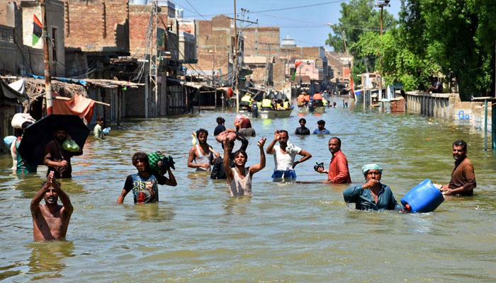 A view of flood affected people in KN Shah city trapped in flood water.— APP /Nadeem Akhtar Soomro