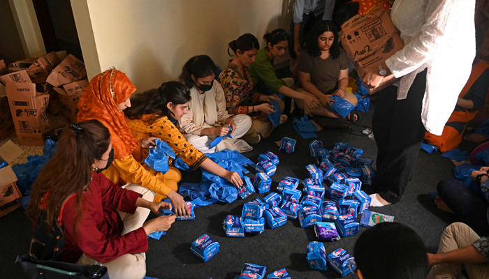 Members of a non-governmental organisation pack sanitary pads for women displaced by massive flooding, in Lahore on August 31, 2022. -AFP