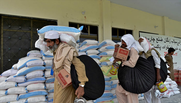 Flood-affected people receive relief supplies from a distribution center after heavy monsoon rains in Charsadda district of Khyber Pakhtunkhwa province on September 11, 2022. —AFP/Abdul MAJEED