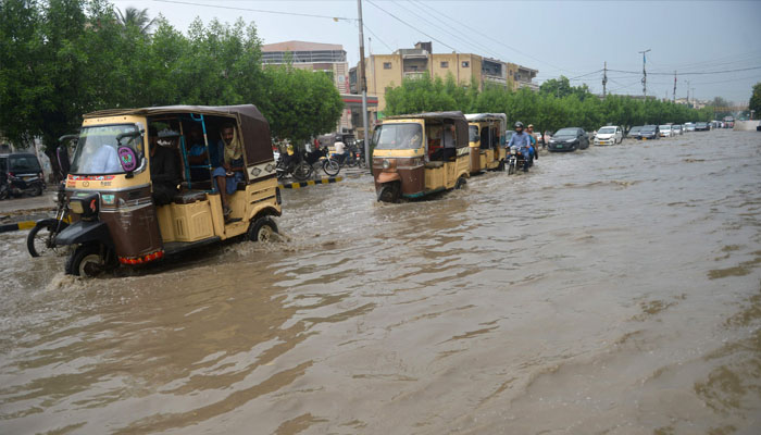 Commuters make their way through a flooded street after heavy rains in Karachi on September 13, 2022. ——AFP/ Rizwan TABASSUM