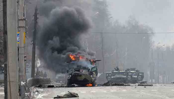 This photograph taken on February 27, 2022 shows a Russian Armoured personnel carrier (APC) burning next to an unidentified soldier´s body during a fight with the Ukrainian armed forces in Kharkiv.-AFP