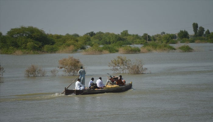 TOPSHOT - Internally displaced people use a boat to cross the flooded area in Dadu district, Sindh province on September 27, 2022. US Secretary of State Antony Blinken called Monday on Pakistan to seek debt relief from its close partner China as floods devastate the South Asian country. —AFP/Rizwan