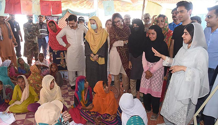 This handout picture taken and released by Chief Minister House Office of Sindh Province on October 12, 2022 shows Nobel Peace laureate Malala Yousafzai (R) speaking with flood-affected children at a makeshift school in Johi, Dadu district of Sindh province. — AFP