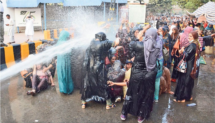 Protesting female healthcare workers seem helpless as anti-riot police resort to using a water cannon to disperse them. — The News