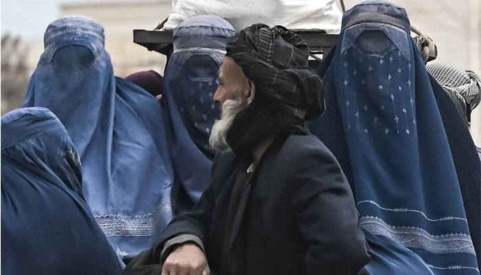 An Afghan man along with burqa-clad Afghan women ride on a vehicle along a road in Mazar-i-Sharif, Afghanistan, Dec. 21, 2021. — AFP