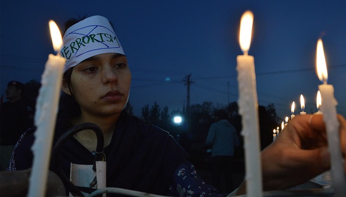 A woman holds a candlelit vigil in memory of students martyred in the APS carnage. – AFP