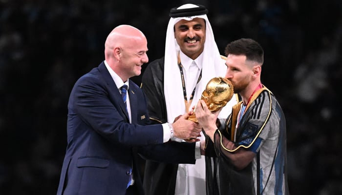 Argentinas captain and forward #10 Lionel Messi receives the FIFA World Cup Trophy from FIFA President Gianni Infantino (C) next to Qatars Emir Sheikh Tamim bin Hamad al-Thani after Argentina won the Qatar 2022 World Cup final football match between Argentina and France at Lusail Stadium in Lusail, north of Doha on December 18, 2022. —AFP