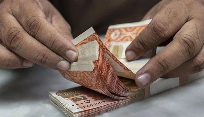 A representational image showing a man counting rupee notes. — AFP/File