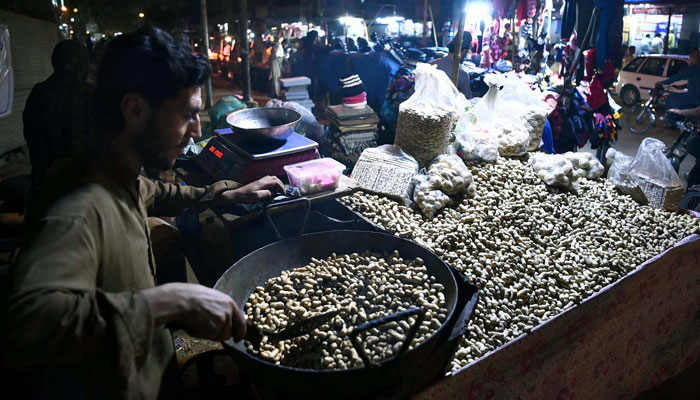 Street vendor busies in roasting peanuts to earn his livelihood for support his family, on the arrival of cold waves of winter season as the use of peanuts increases immunity power during winters, at a roadside stall in Karachi on Saturday, January 21, 2023. — PPI