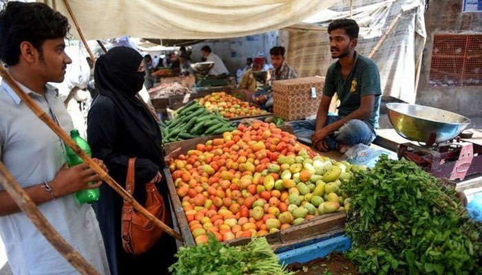 Shoppers seen interacting with a vegetable vendor in a market. The News/File