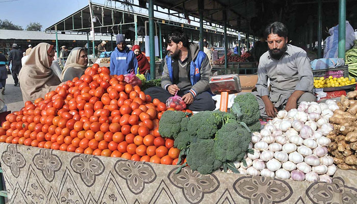 People buying vegetable from a stall in a local market. — APP