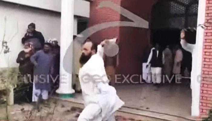 A political party worker throws a stone at his opponent during the riot outside the ECP office in Multan. — Screengrab via YouTube/Geo News Live