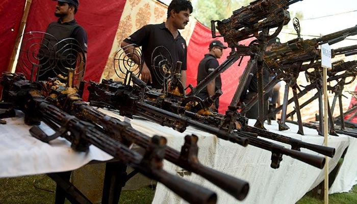 An undated image of policemen standing beside seized weapons displayed for the media in Karachi. —AFP/File