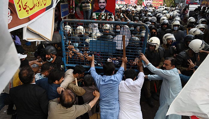 Supporters (foreground) of former prime minister Imran Khan and riot police scuffle outside Khan´s house to prevent officers from arresting him, in Lahore on March 14, 2023. —AFP