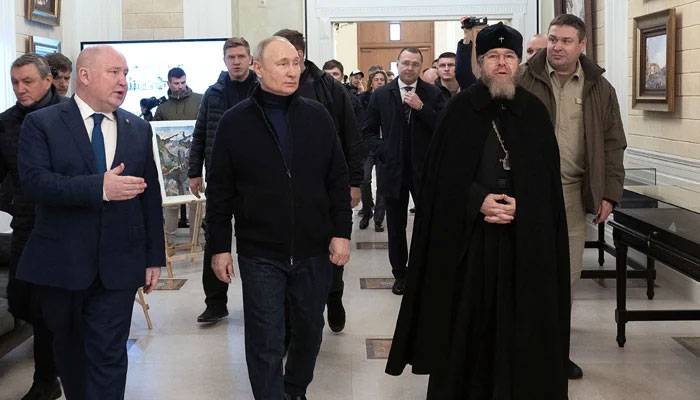 This photograph shows Russian President Vladimir Putin (C), flanked by Metropolitan Tikhon Shevkunov (R), chairman of the Patriarchal Council for Culture, listening to Sevastopol Governor Mikhail Razvozhayev (L), as he visits the Chersonesos Taurica historical and archaeological park on the 9th anniversary of the referendum on the state status of Crimea and Sevastopol and its reunification with Russia on March 18, 2023. — AFP
