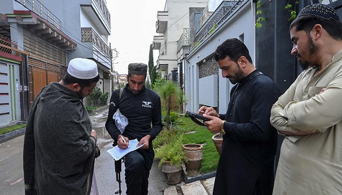 An official (2R) from the Pakistan Bureau of Statistics uses a digital device to collect information from residents (L and R) during the first-ever door-to-door digital national census in Peshawar on March 25, 2023. — AFP
