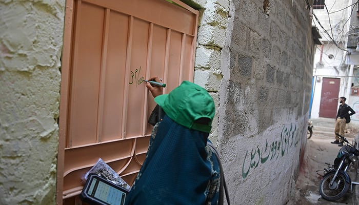 An official from the Pakistan Bureau of Statistics holds a digital device as she marks a house after collecting information from a resident during door-to-door the first-ever digital national census in Karachi on March 1, 2023. — AFP
