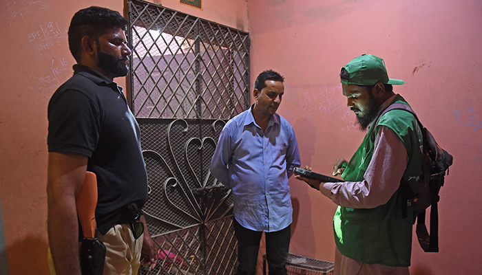 An official (R) from the Pakistan Bureau of Statistics uses a digital device to collect information from a resident during door-to-door the first-ever digital national census in Karachi on March 1, 2023. — AFP
