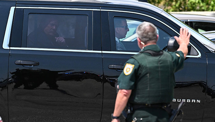 A policeman waves at former US President Donald Trump as he arrives at Palm Beach International Airport in West Palm Beach, Florida, on April 3, 2023.—AFP