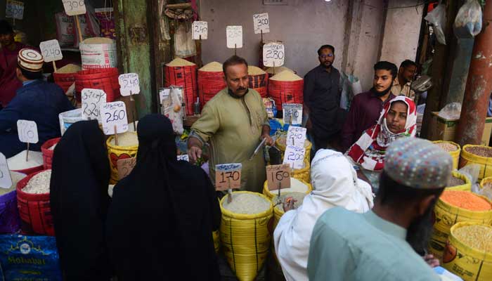 This file photo shows people gathered around a stall in a market place in Pakistan. — AFP