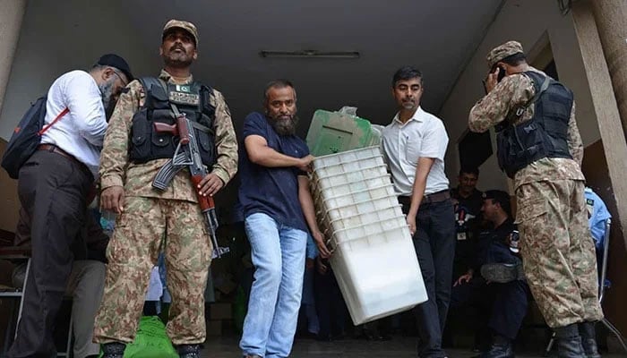 Soldiers stand guard as election officials carry election materials at a distribution centre in Islamabad. — AFP/File