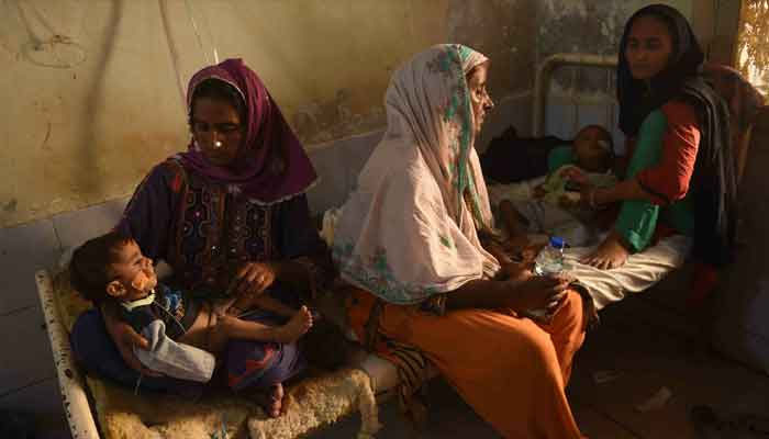 Women take care of their sick children at a makeshift medical camp set for people displaced by floods in Dadu district, Sindh on September 27, 2022. — AFP